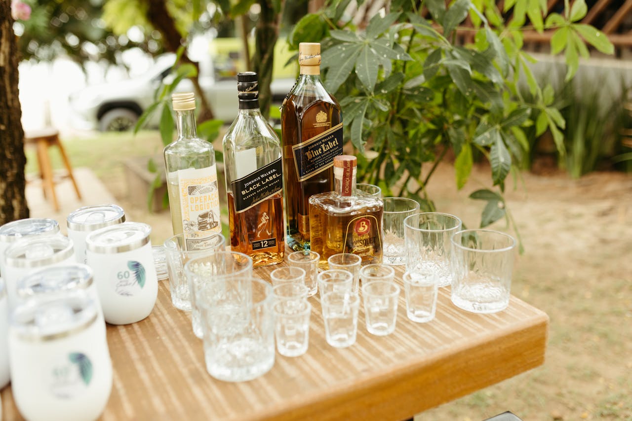 An elegant outdoor table setting with whiskey bottles and glasses for a tasting event.